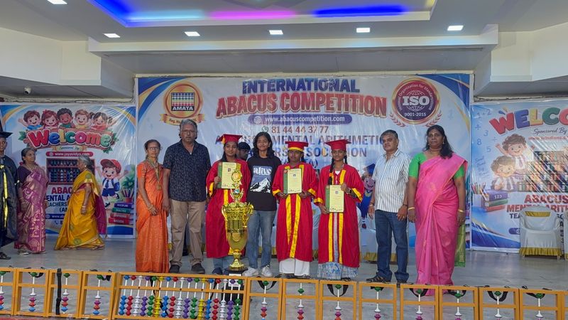 Students holding certificates beside a large trophy at an Abacus event